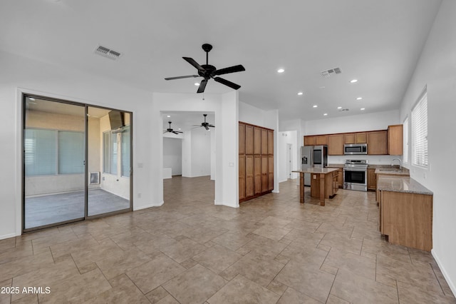 kitchen featuring sink, a kitchen island, light stone countertops, and appliances with stainless steel finishes