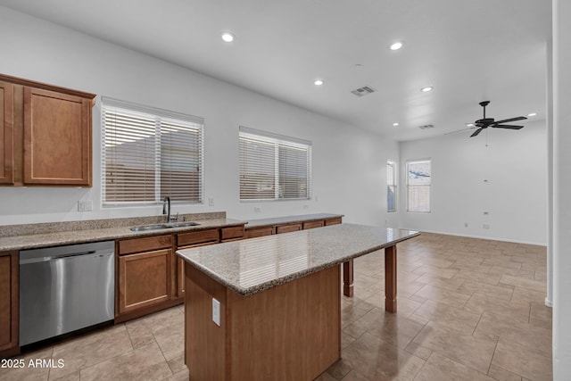 kitchen with dishwasher, sink, a center island, ceiling fan, and light stone counters