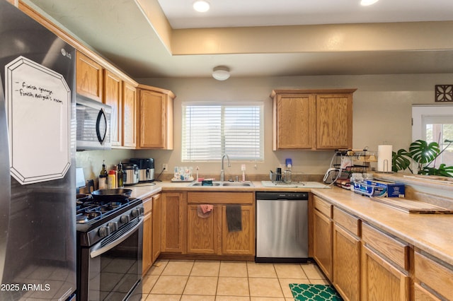 kitchen with appliances with stainless steel finishes, light countertops, a sink, and light tile patterned flooring