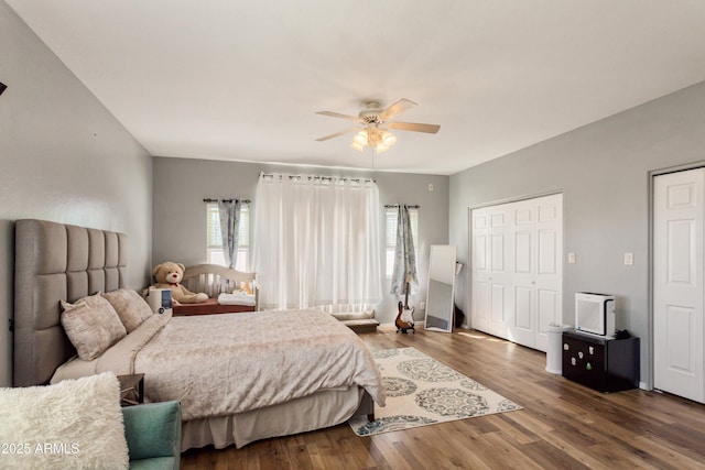 bedroom with multiple closets, ceiling fan, and dark wood-type flooring