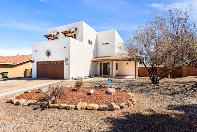 view of front facade featuring a garage, concrete driveway, fence, and stucco siding