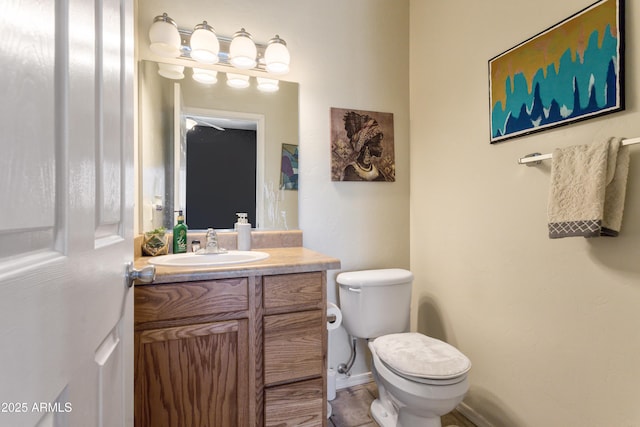 half bathroom with toilet, baseboards, and vanity