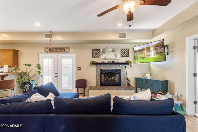 living room featuring light tile patterned floors, french doors, a fireplace, and visible vents