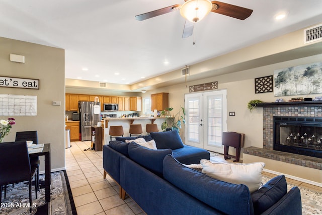 living area with french doors, light tile patterned floors, recessed lighting, visible vents, and a tiled fireplace