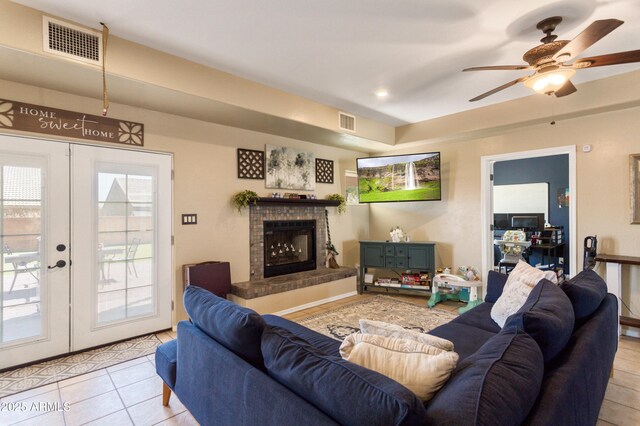 living room featuring french doors, visible vents, a fireplace, and light tile patterned floors