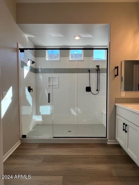 bathroom featuring vanity, hardwood / wood-style flooring, and a shower with door