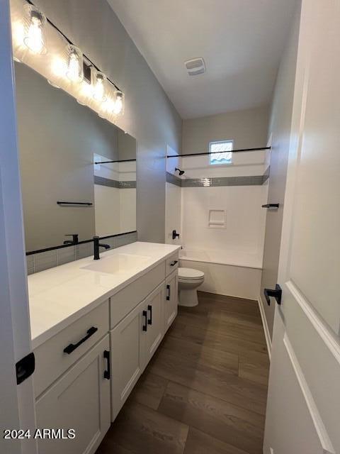 full bathroom featuring shower / washtub combination, vanity, wood-type flooring, and toilet