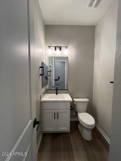 bathroom with toilet, vanity, and hardwood / wood-style flooring