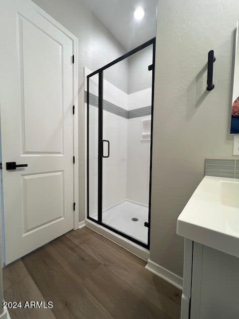 bathroom with vanity, wood-type flooring, and a shower with door