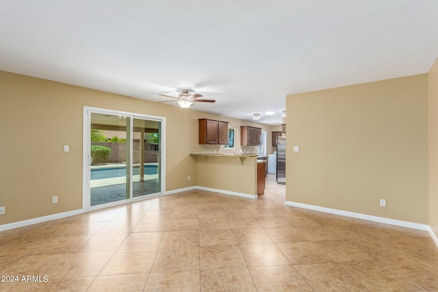 unfurnished living room featuring ceiling fan and light tile patterned floors