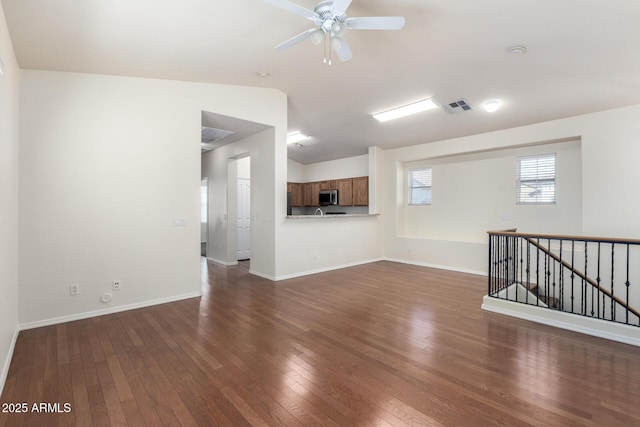 unfurnished living room featuring baseboards, visible vents, dark wood finished floors, lofted ceiling, and ceiling fan