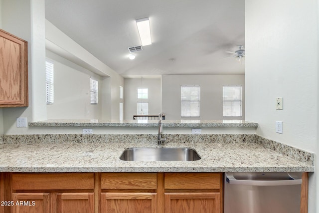 kitchen with visible vents, a sink, light stone countertops, vaulted ceiling, and stainless steel dishwasher