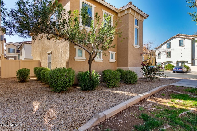 view of home's exterior featuring stucco siding, fence, and a tiled roof