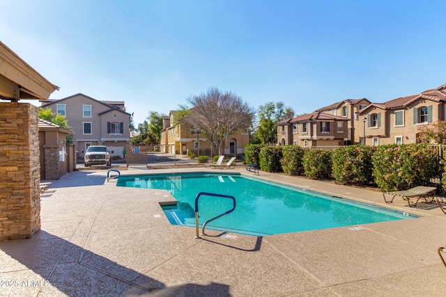 pool with a patio area, a residential view, and fence