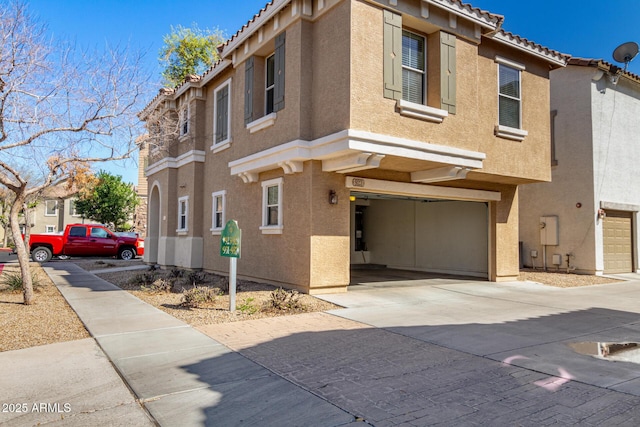 view of property featuring stucco siding, a garage, driveway, and a tiled roof