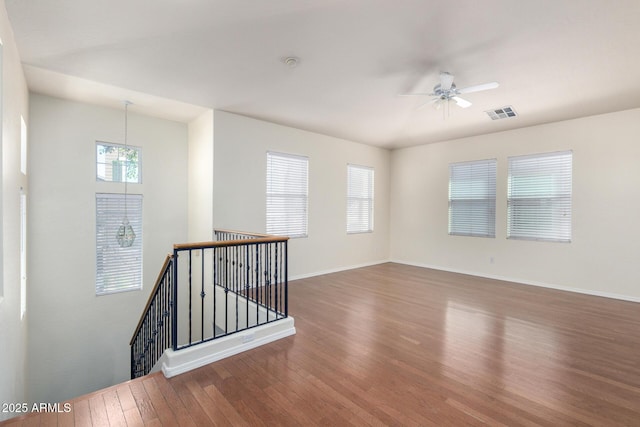 empty room featuring hardwood / wood-style floors, baseboards, visible vents, and ceiling fan