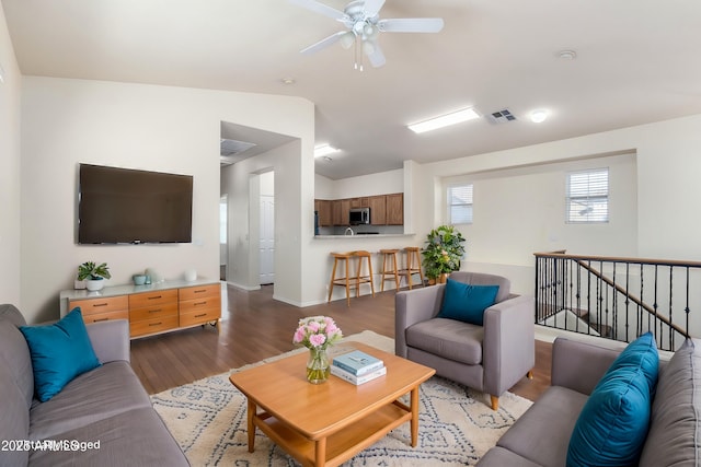 living room featuring lofted ceiling, wood finished floors, visible vents, and ceiling fan