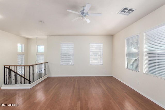 unfurnished room with visible vents, a ceiling fan, baseboards, and hardwood / wood-style floors