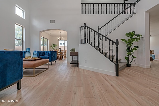 living room with a high ceiling, a chandelier, and light hardwood / wood-style floors