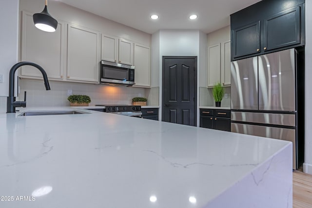 kitchen featuring stainless steel appliances, decorative backsplash, decorative light fixtures, light stone countertops, and sink