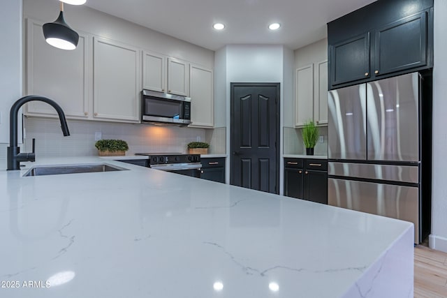 kitchen featuring appliances with stainless steel finishes, decorative backsplash, light stone counters, and sink