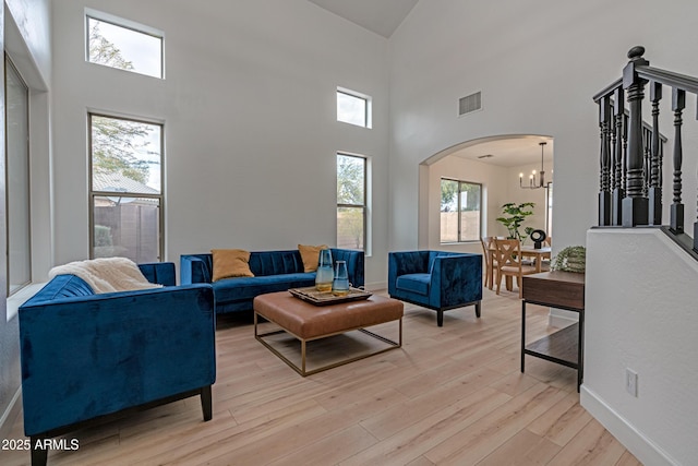 living room with an inviting chandelier, a high ceiling, and light hardwood / wood-style floors