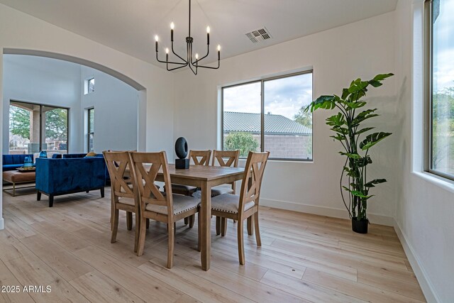 dining room with light wood-type flooring and a notable chandelier