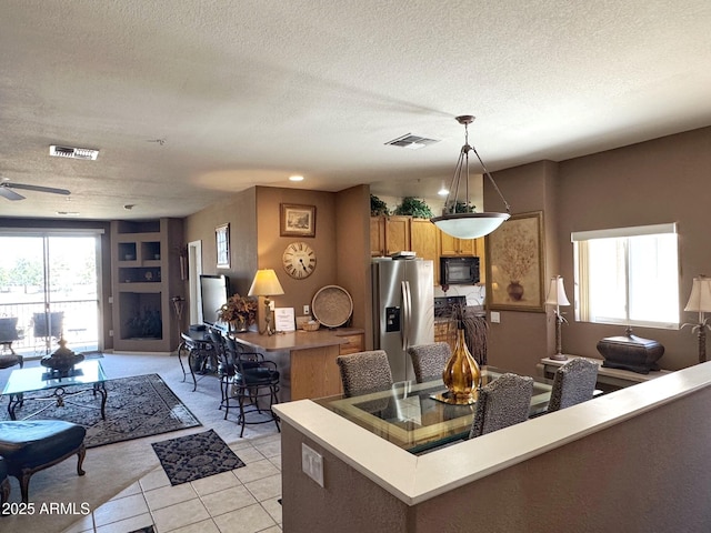 6535 E Superstition Springs Blvd Unit 217, Mesa, AZ 85206 - kitchen featuring stainless steel fridge, black microwave, light tile patterned flooring, brown cabinets, and a textured ceiling