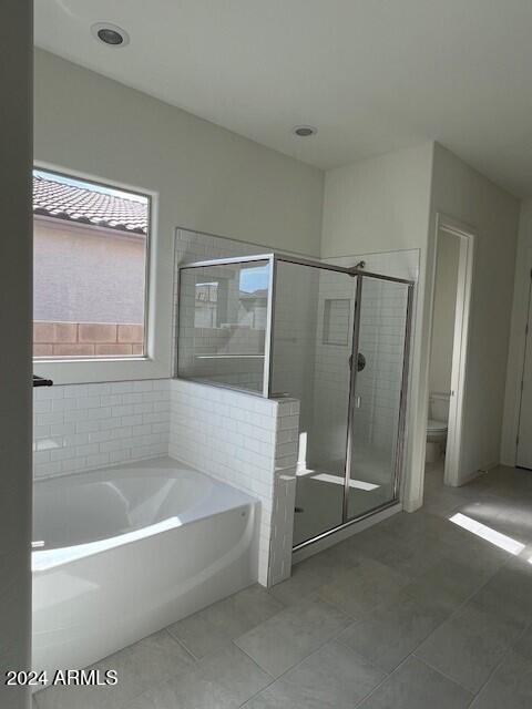 bathroom with tile patterned flooring, toilet, and separate shower and tub