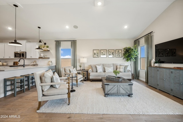 living room with vaulted ceiling, sink, and light hardwood / wood-style flooring