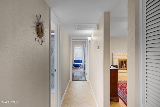 hallway with visible vents, baseboards, and light tile patterned floors