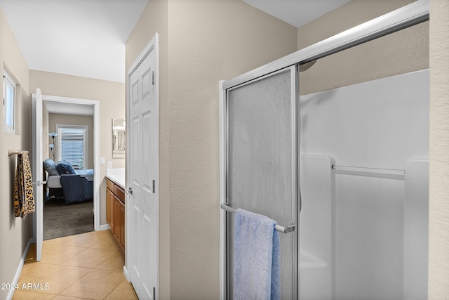 full bath featuring a stall shower, baseboards, connected bathroom, tile patterned flooring, and vanity