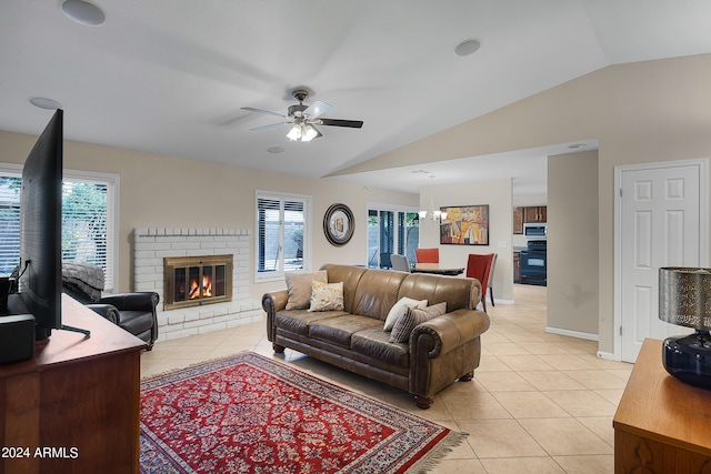 living area with a fireplace, light tile patterned flooring, vaulted ceiling, baseboards, and ceiling fan with notable chandelier