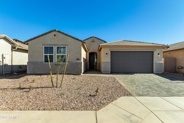 view of front of property with a tiled roof, decorative driveway, an attached garage, and stucco siding