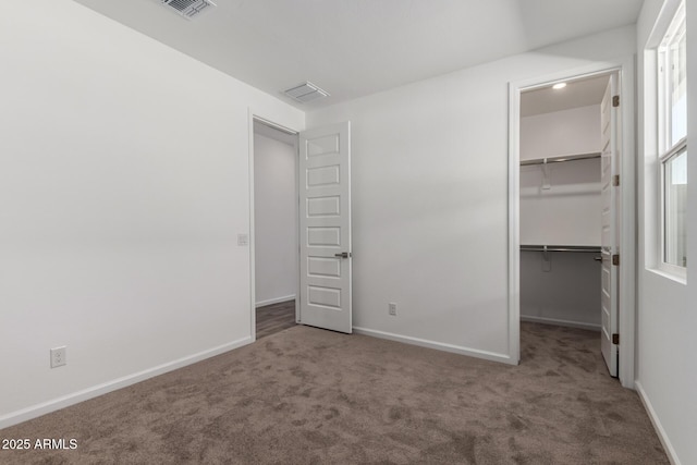 unfurnished bedroom featuring a walk in closet, carpet floors, and a closet