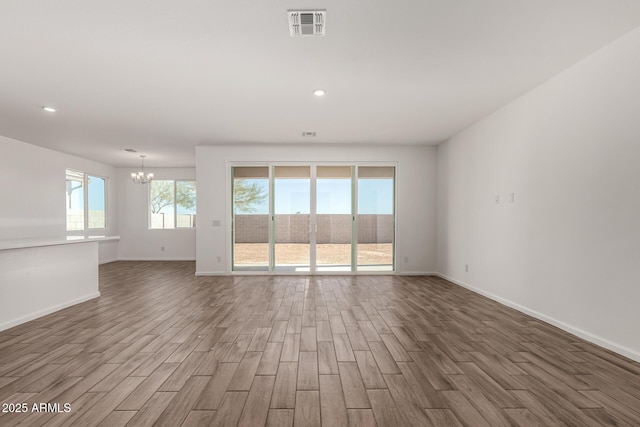 empty room featuring an inviting chandelier and hardwood / wood-style floors