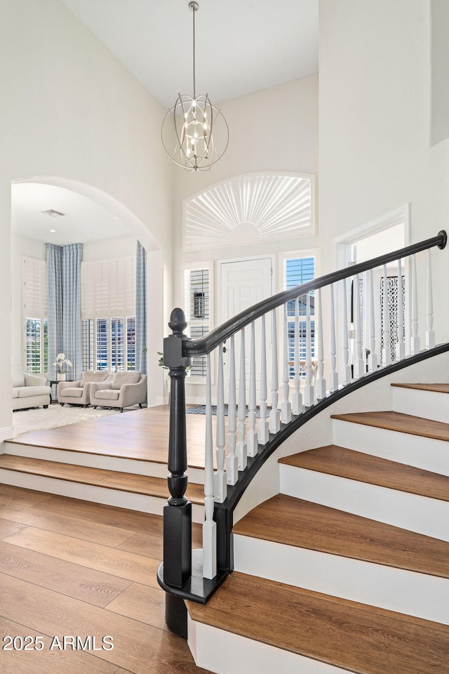3665 S Jojoba Way, Chandler, AZ 85248 - stairs with a towering ceiling, wood finished floors, arched walkways, and a chandelier
