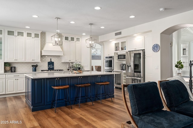 3665 S Jojoba Way, Chandler, AZ 85248 - kitchen featuring stainless steel appliances, custom range hood, arched walkways, light countertops, and wood finished floors