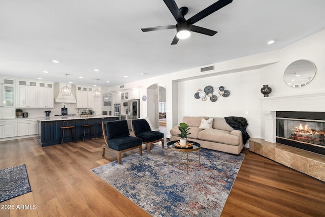 3665 S Jojoba Way, Chandler, AZ 85248 - living room with arched walkways, a ceiling fan, light wood-style floors, a glass covered fireplace, and recessed lighting