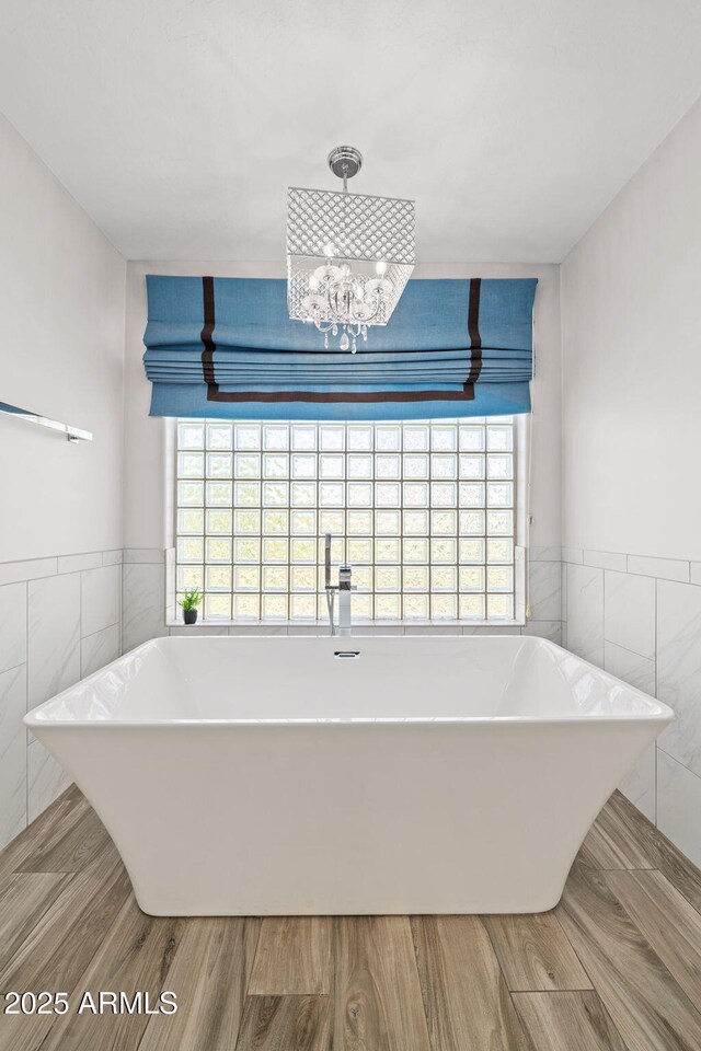 3665 S Jojoba Way, Chandler, AZ 85248 - bathroom with tile walls, a soaking tub, a chandelier, wood finished floors, and wainscoting