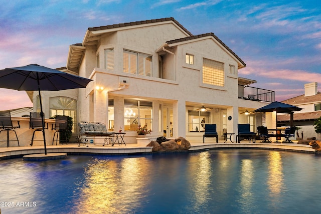3665 S Jojoba Way, Chandler, AZ 85248 - back of house at dusk with a balcony, a patio, an outdoor pool, and stucco siding