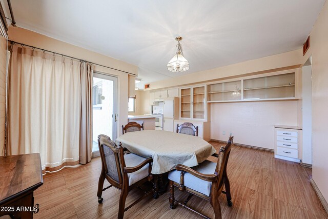 dining area featuring a notable chandelier, visible vents, light wood-style flooring, and baseboards