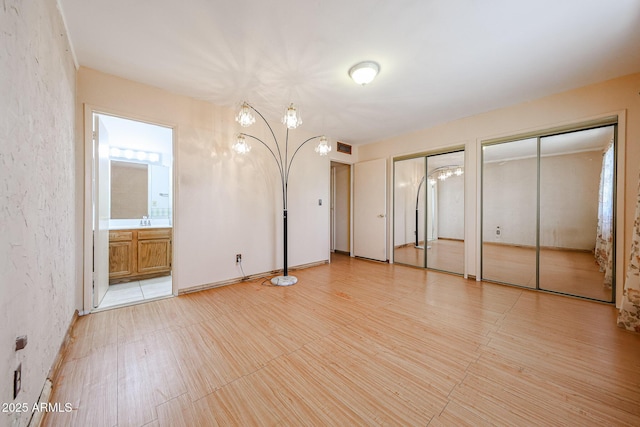 unfurnished bedroom featuring a sink, visible vents, multiple closets, and ensuite bathroom