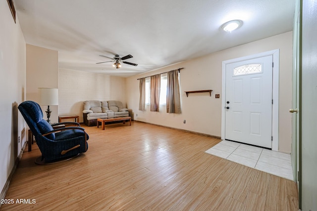 entryway with baseboards, light wood-style flooring, and a ceiling fan