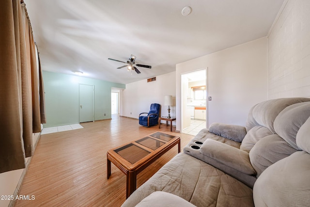 living room with a ceiling fan, visible vents, light wood-type flooring, and baseboards