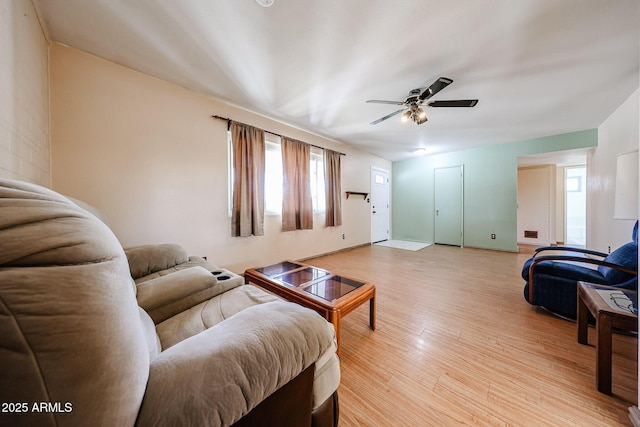 living area featuring baseboards, ceiling fan, and light wood finished floors