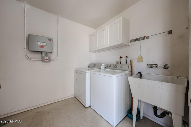 clothes washing area with washer and clothes dryer, cabinet space, light floors, and a sink