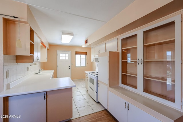 kitchen featuring light countertops, light tile patterned floors, decorative backsplash, electric stove, and a sink