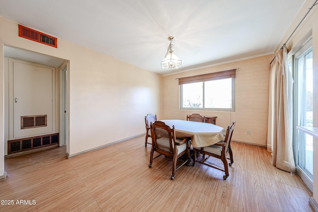 dining room featuring visible vents, plenty of natural light, and brick wall