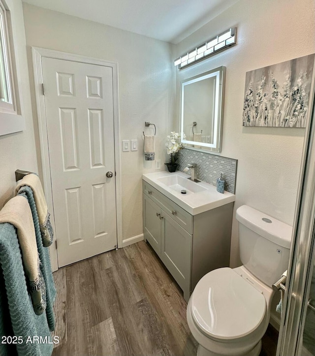 bathroom with wood-type flooring, toilet, decorative backsplash, and vanity